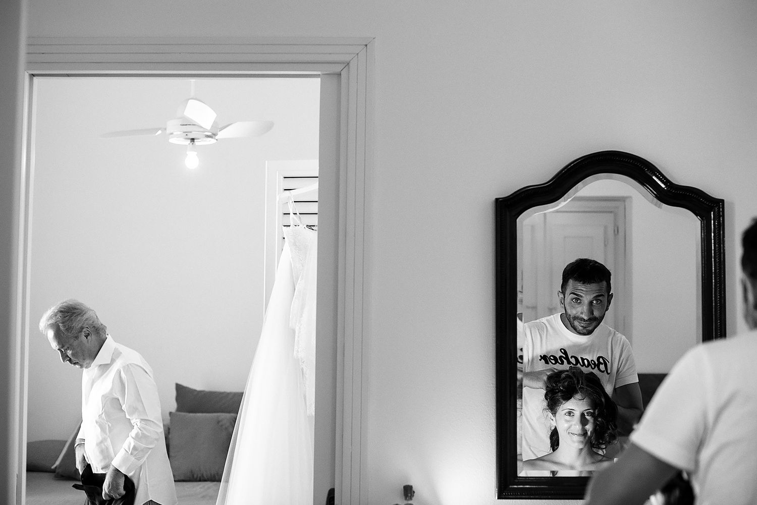 Black and white image of elegant wedding dresses hanging in a dressing room.