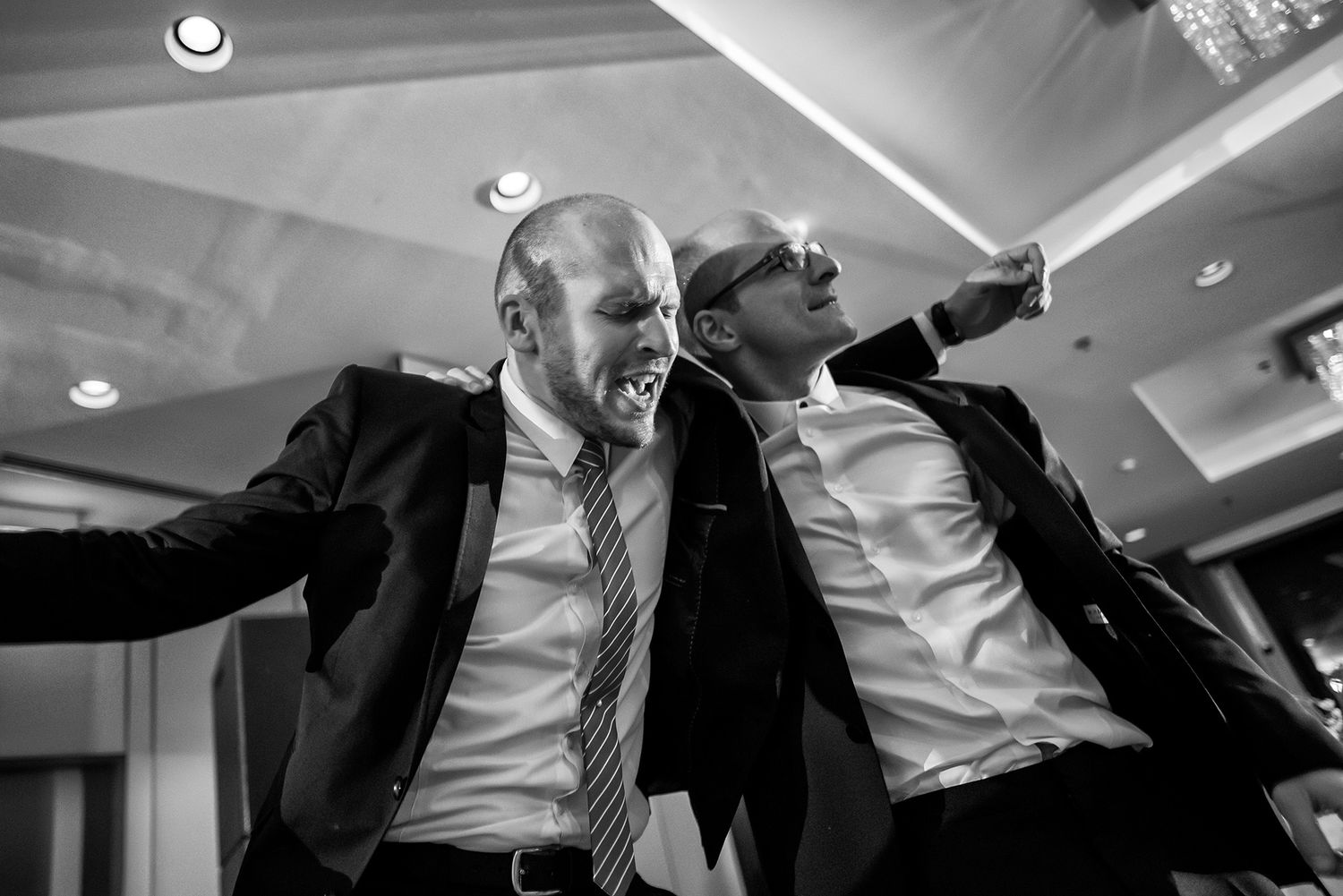Dynamic black and white shots of wedding guests dancing at a reception.