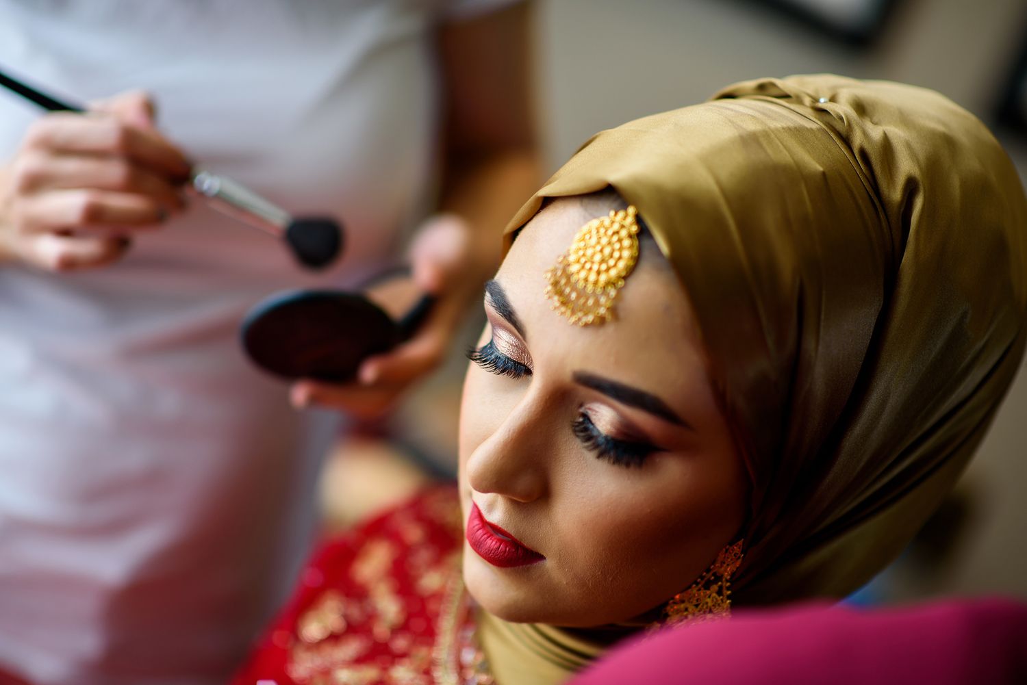 Close-up details of traditional wedding jewelry and makeup in warm tones.