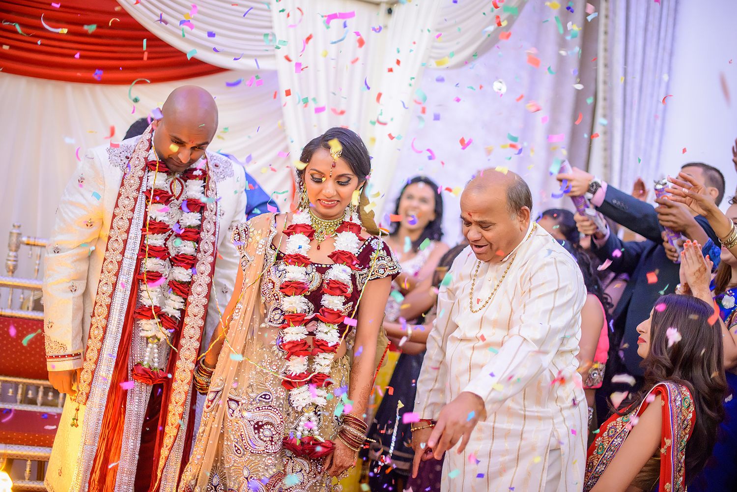 Festive wedding celebration with white and red draped decorations and confetti.