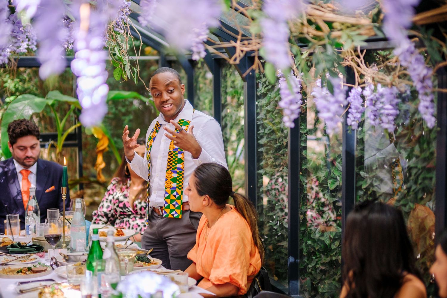 Outdoor wedding celebration with hanging purple wisteria and lush greenery decorations.