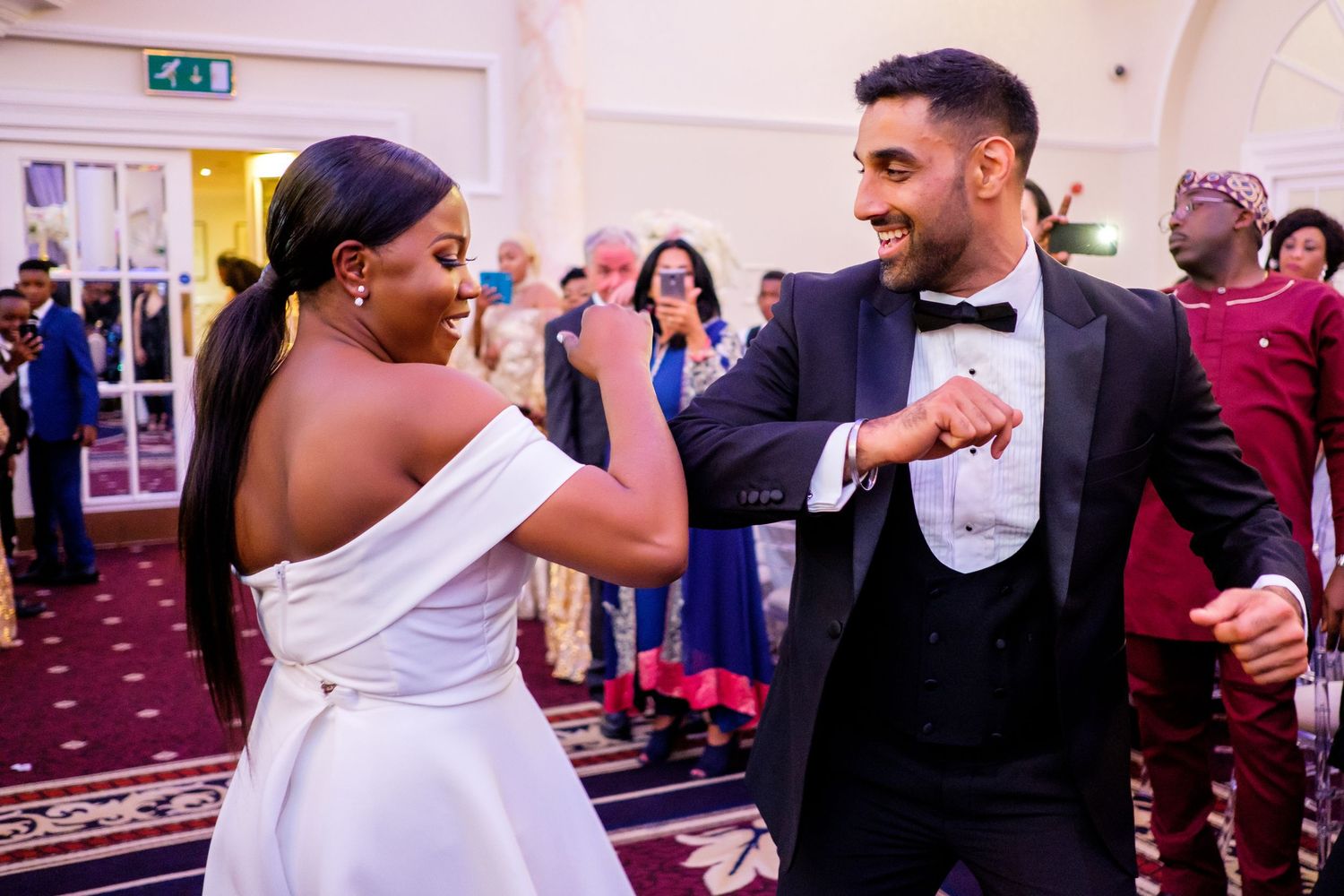 Wedding celebration with dancing couples in formal attire enjoying themselves at an elegant reception.