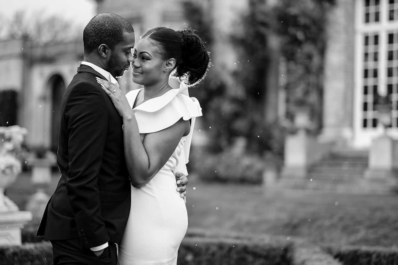 A romantic moment captured in black and white photography on mansion grounds.