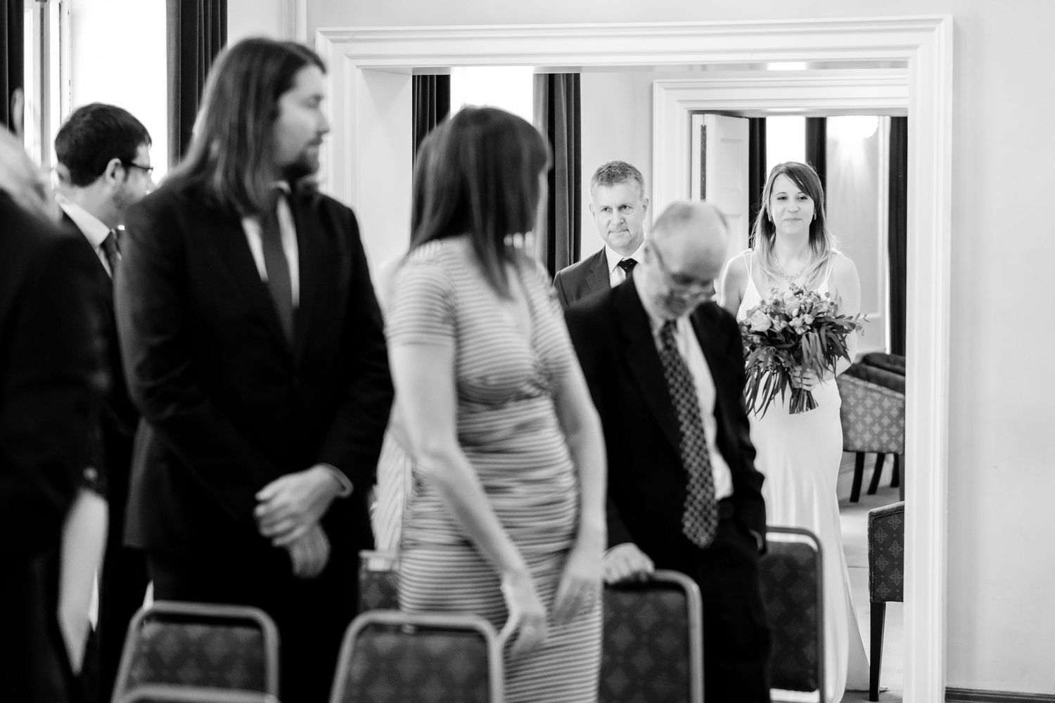 Black and white candid wedding reception scene with guests mingling.