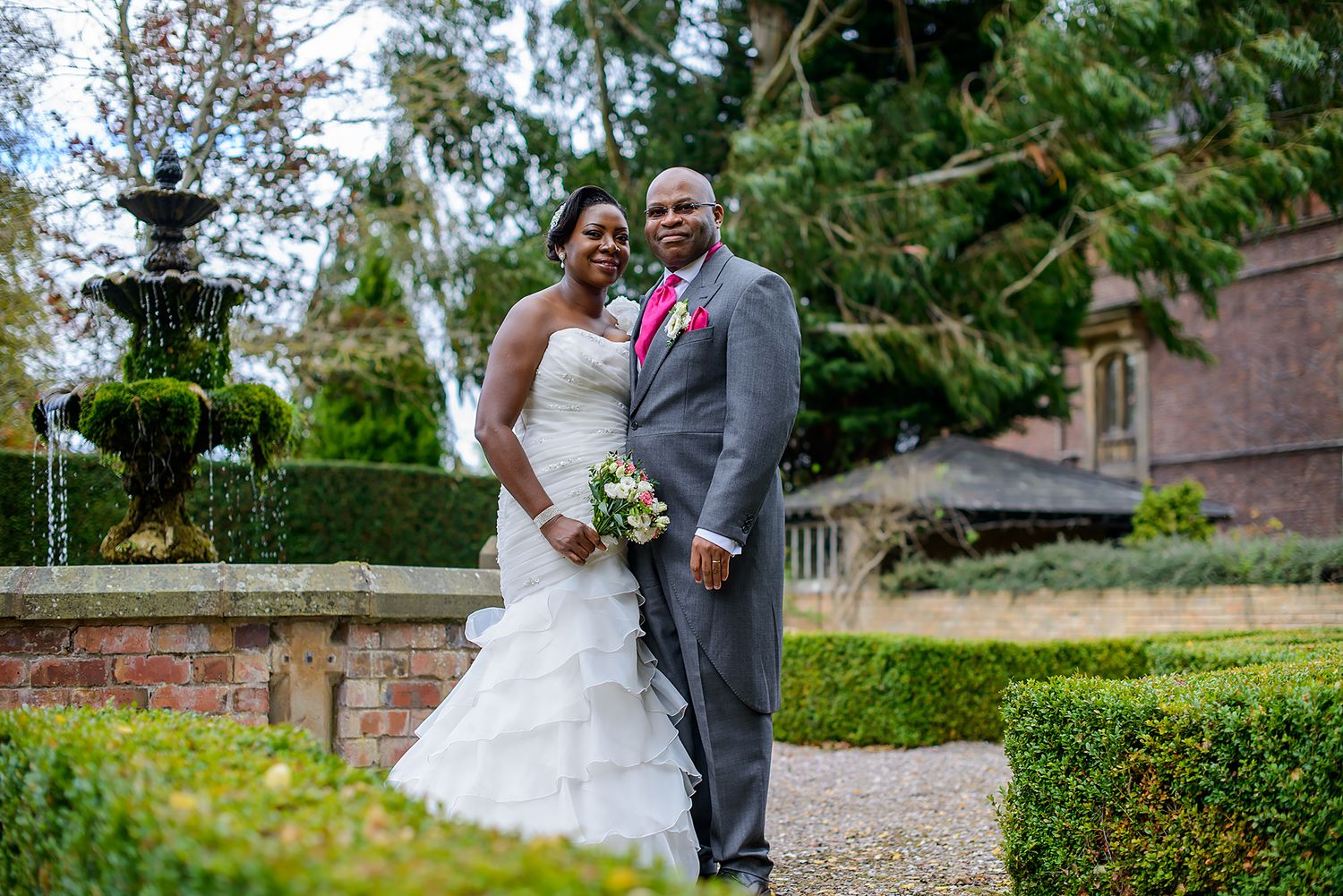 Romantic wedding portraits taken in a manicured garden with stone architecture.