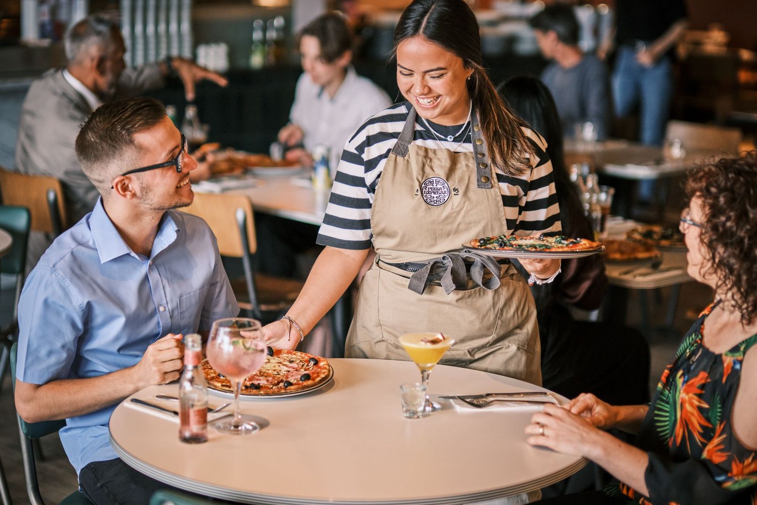 Restaurant patrons enjoying food and drinks at tables in a casual dining atmosphere.