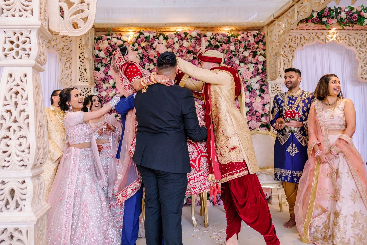 Elegant wedding celebration in an ornately decorated ballroom with pink and white floral arrangements.