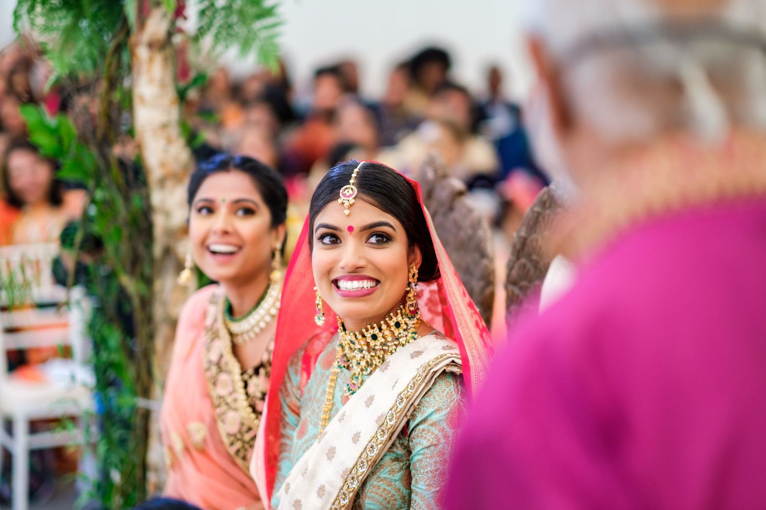 Guests celebrate joyfully at an outdoor Indian wedding ceremony with vibrant decorations and traditional attire.