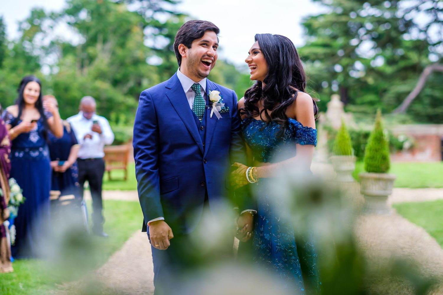 Wedding guests enjoying candid moments in a lush garden setting.