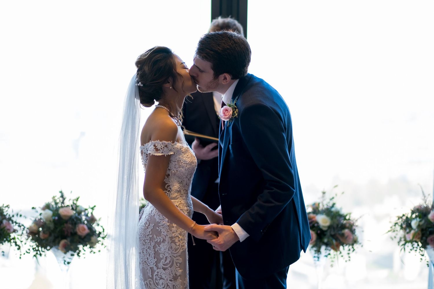 A couple shares an intimate moment during their wedding reception with floral arrangements in the background.