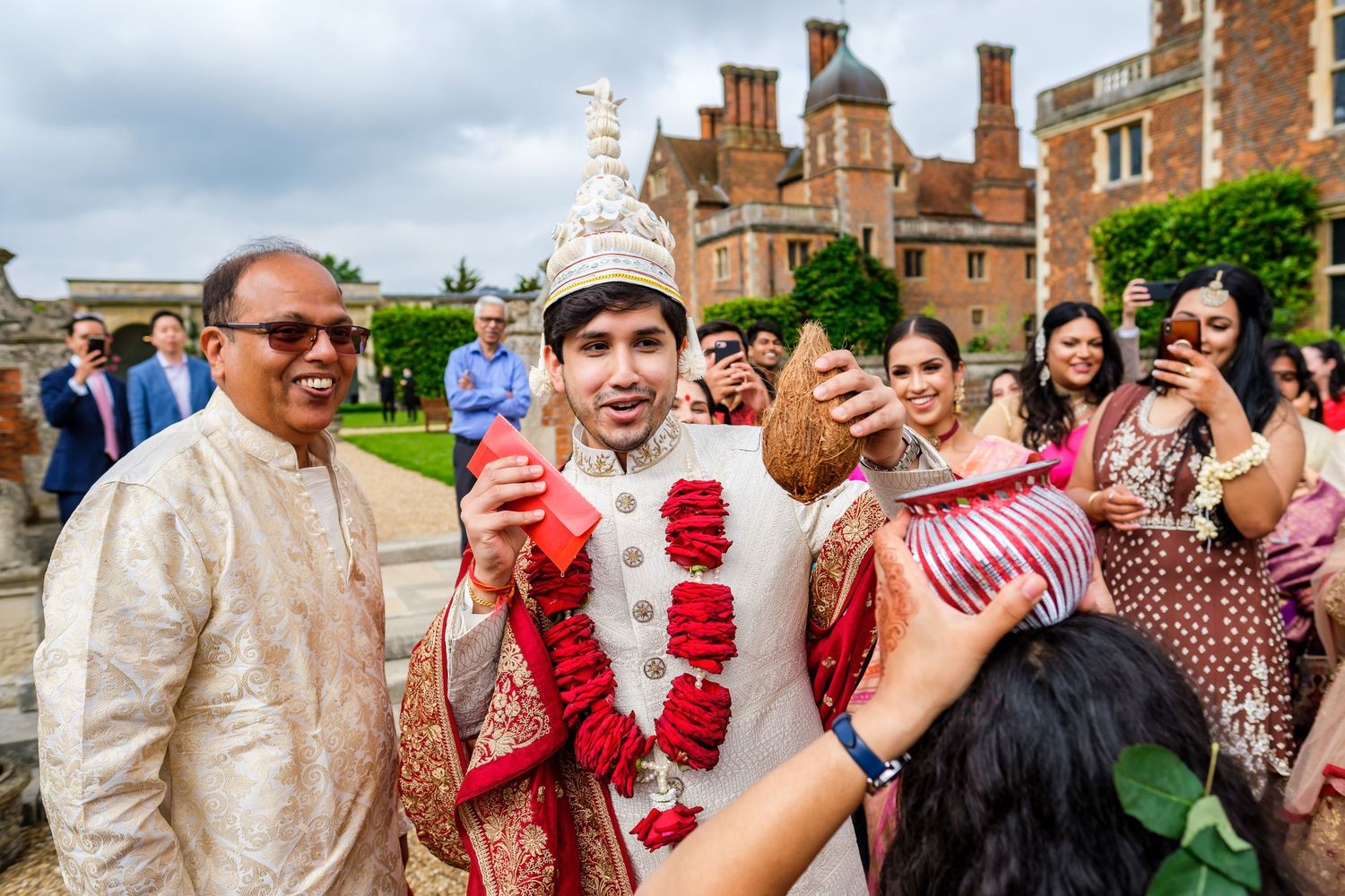 Guests celebrate and laugh during an outdoor wedding reception with brick buildings in the background.
