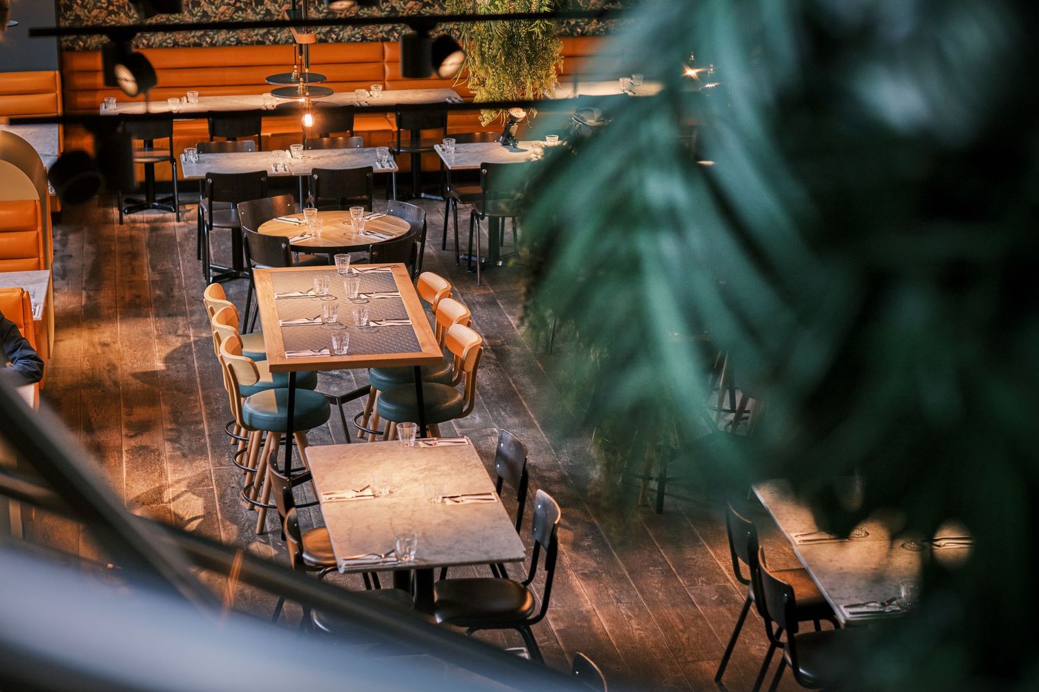 Rustic restaurant interior with wooden tables and chairs illuminated by soft evening lighting.