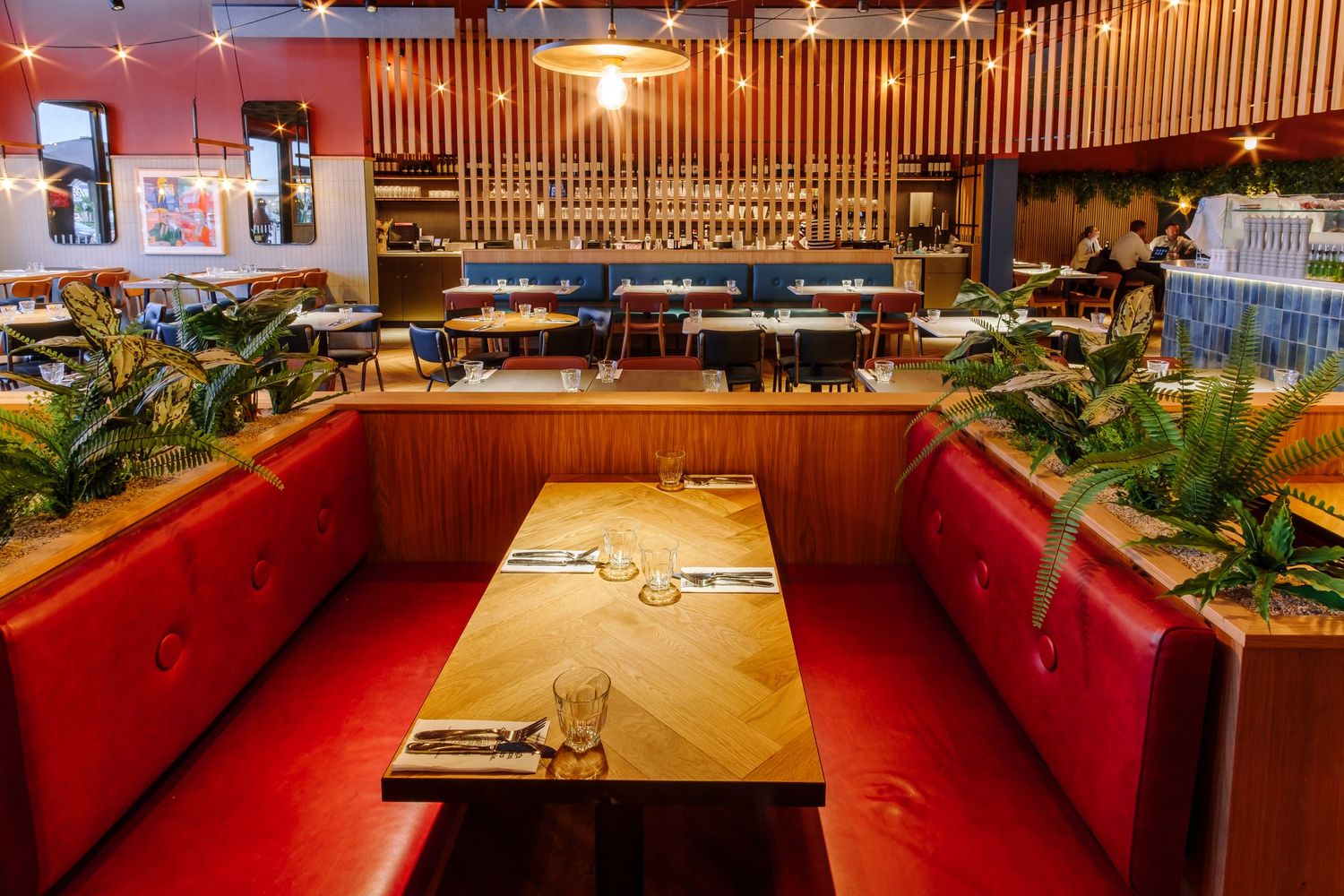Restaurant dining area with red booth seating and wooden accents under ambient lighting.