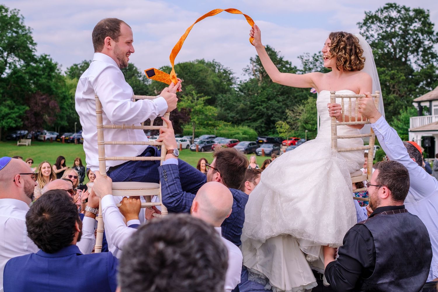 Wedding guests form a circle during outdoor reception celebration.