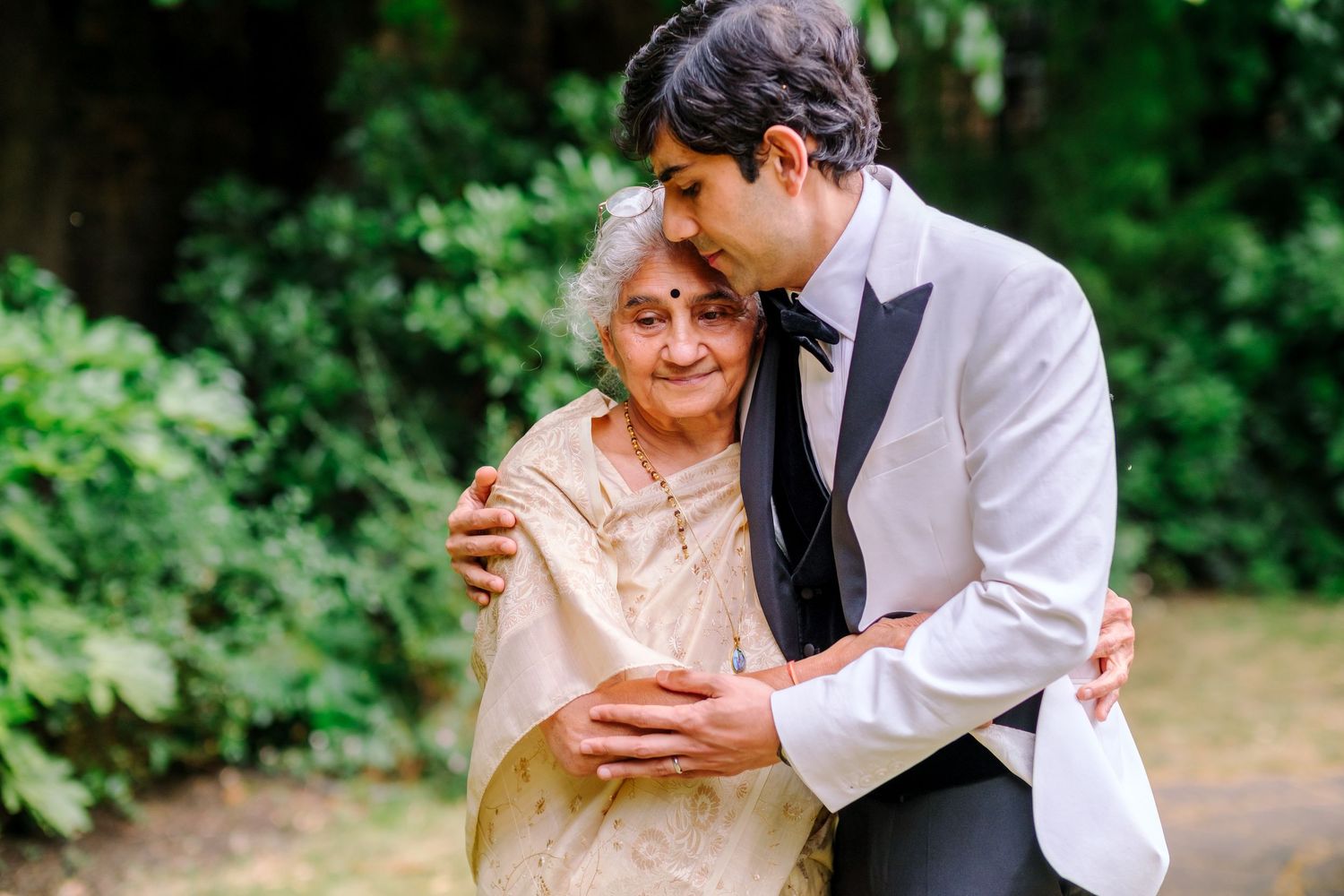 Couple sharing an intimate moment in a lush garden setting during a wedding celebration.