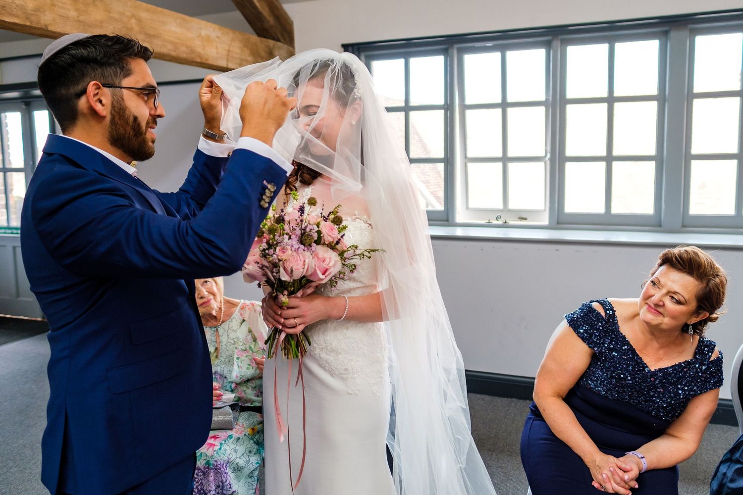 Wedding celebration in a bright modern venue with industrial windows and elegant decor.