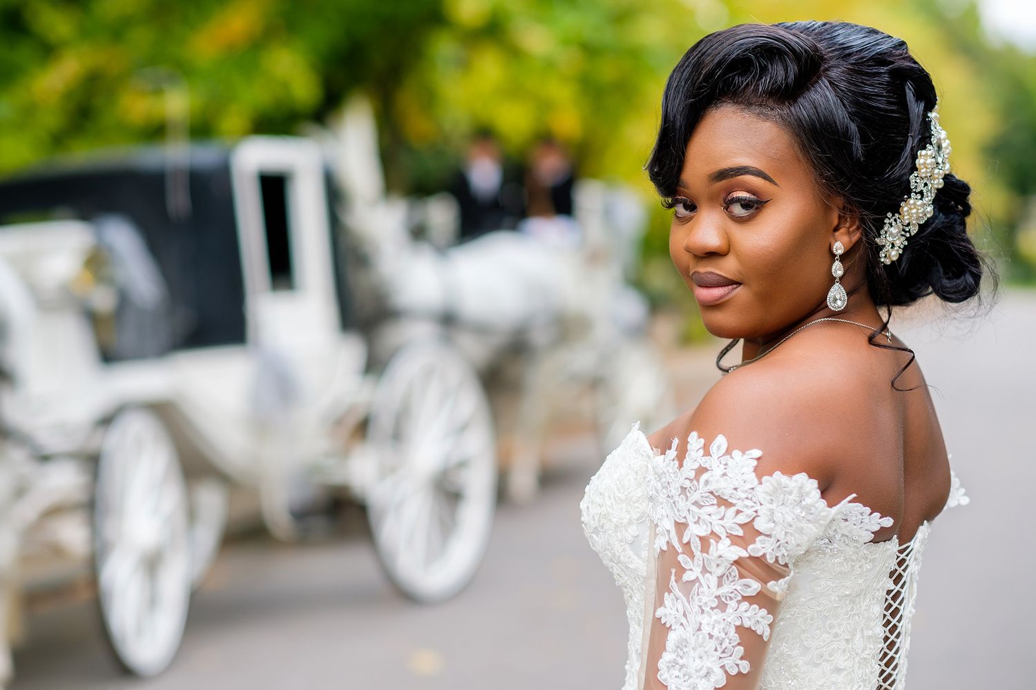 Wedding party posing near a decorative white carriage in a garden setting.