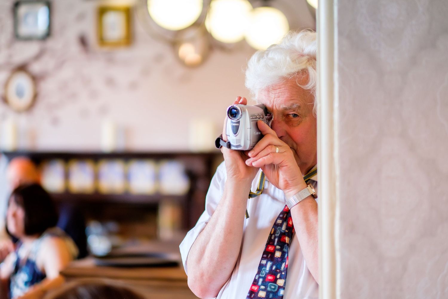 Person wearing floral dress takes photo with vintage camera in dimly lit room.