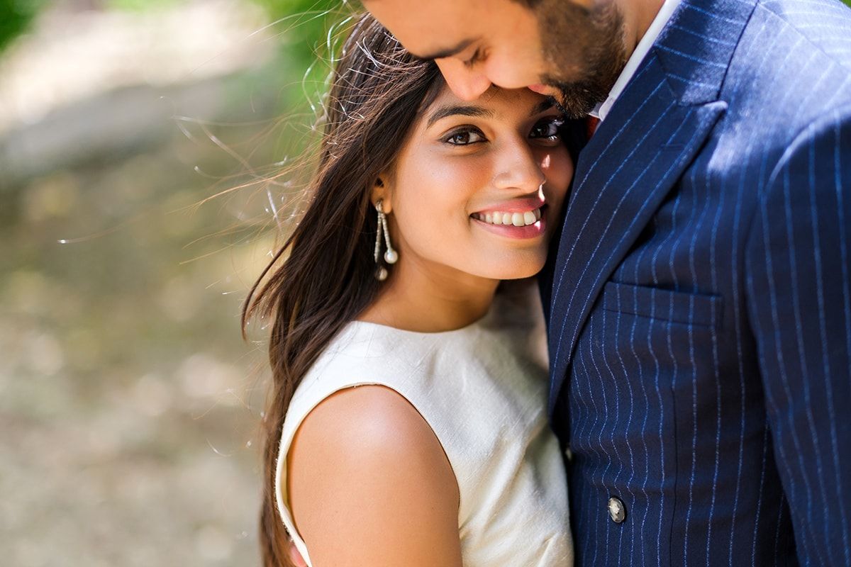 Couple sharing an intimate moment in a sunlit garden setting.