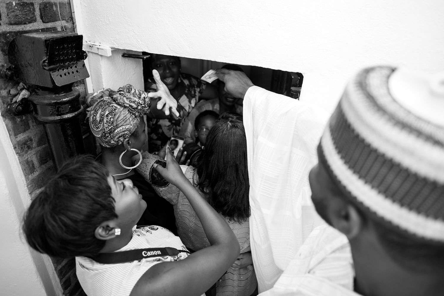 A candid black and white photo showing joyous laughter and celebration during a social gathering.
