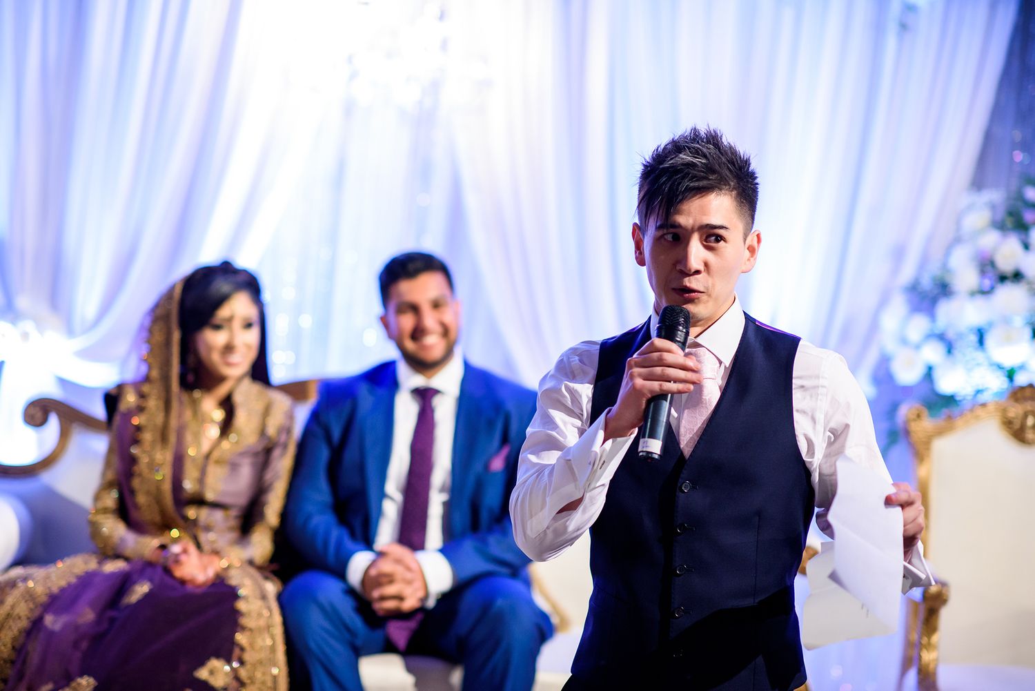 Indoor wedding reception with white drapery and blue accent lighting creating an elegant atmosphere.