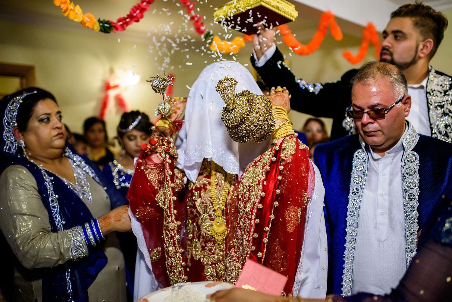 Wedding celebration features bright marigold and red garland decorations.