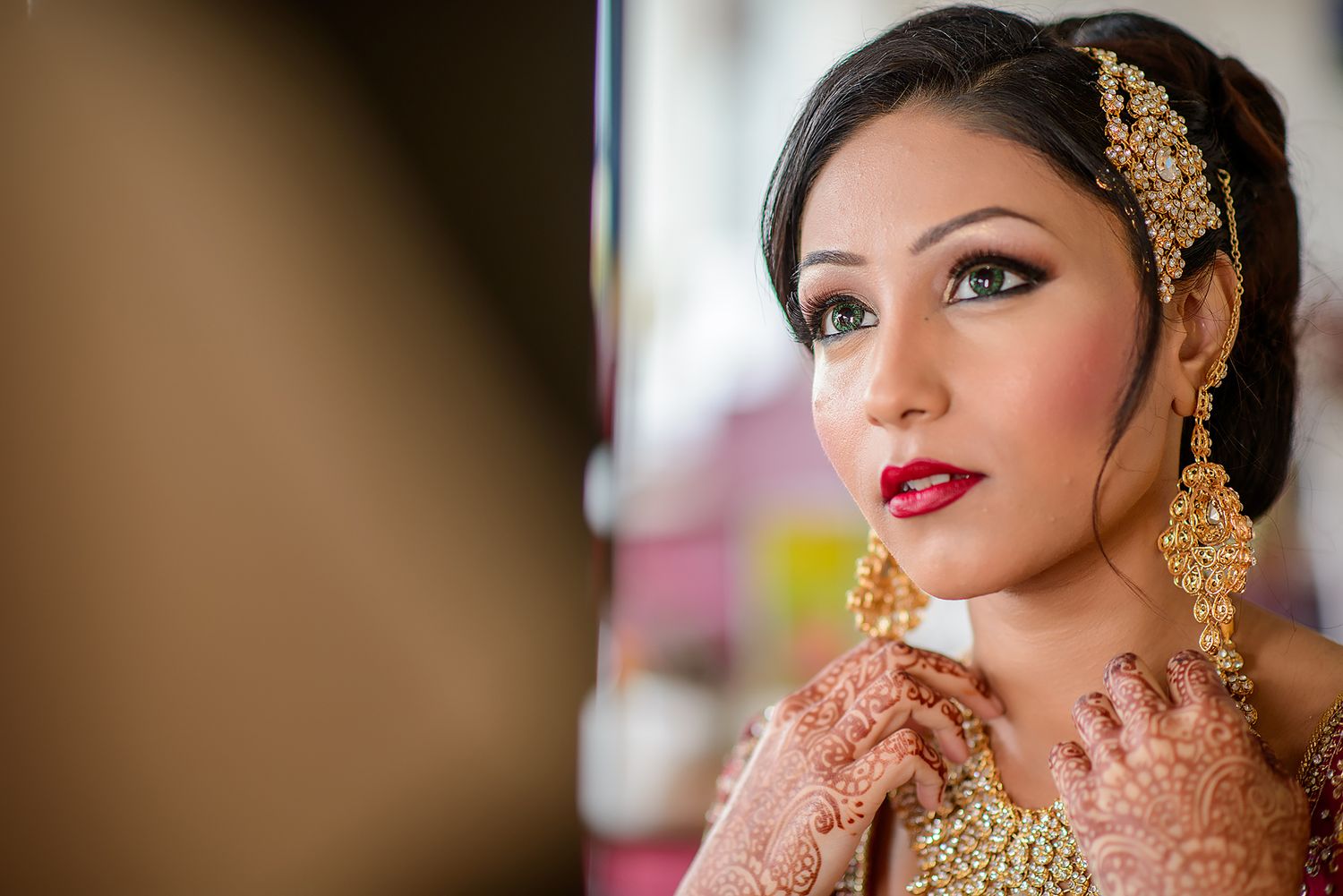 Traditional South Asian bridal portrait showcasing ornate gold jewelry and detailed makeup.