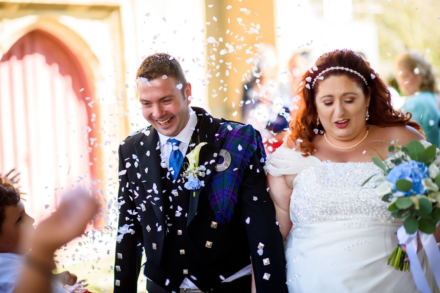 Newlyweds celebrating amidst a shower of white confetti.