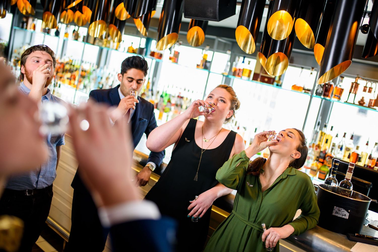 Group of friends laughing together at an upscale bar with pendant lighting.