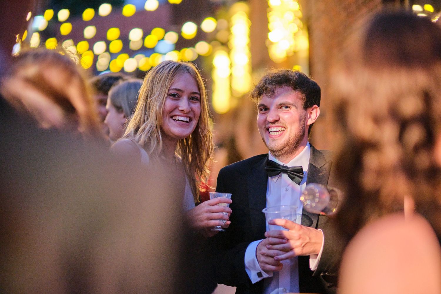 People enjoying drinks and conversation at an elegant indoor evening event with warm lighting.