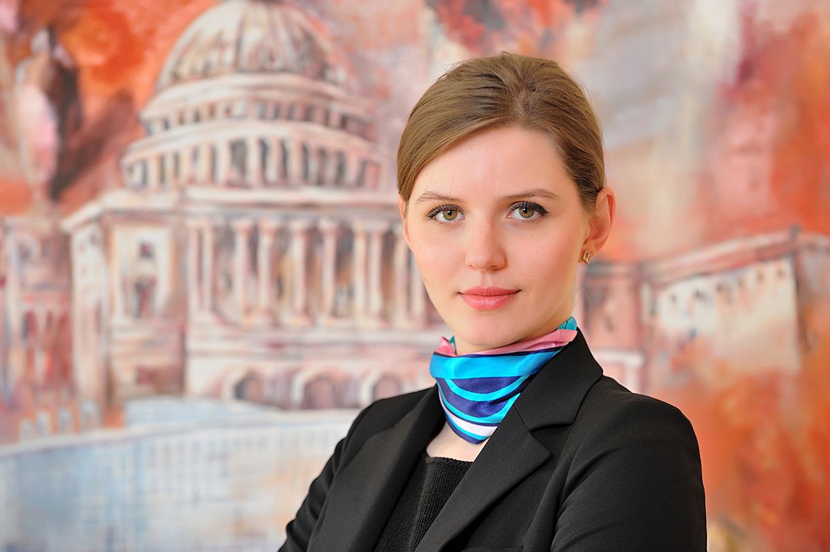 Professional headshot series with blue scarf accessory against vibrant orange and red architectural backdrop.