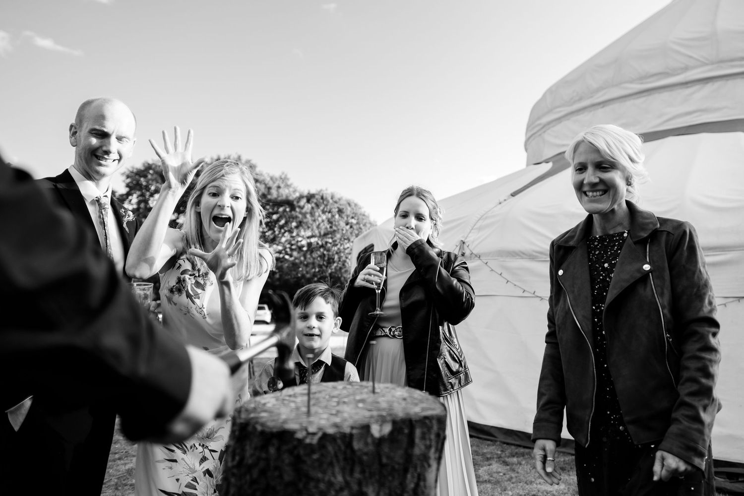 Wedding guests enjoying candid moments under a white tent at an outdoor reception.