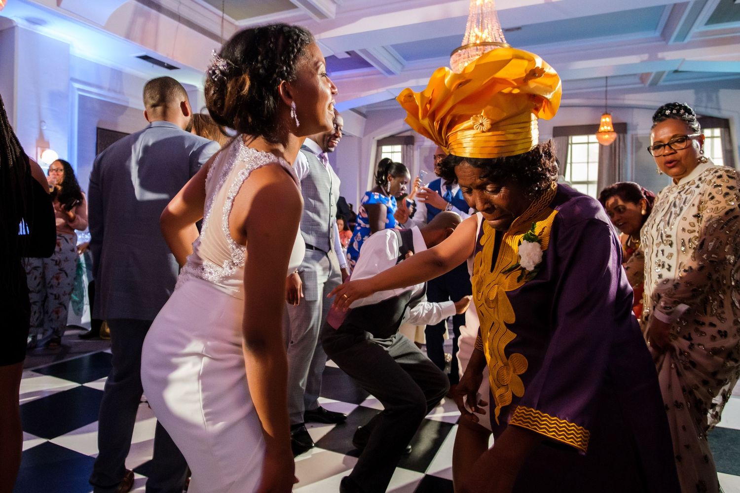 Wedding reception dance floor filled with guests under colorful lighting.