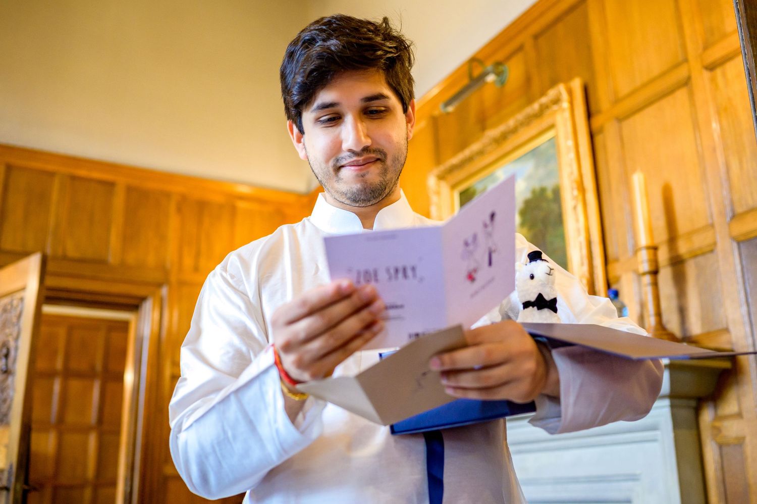 A person in a white chef's coat reads paperwork in a wood-paneled kitchen interior.