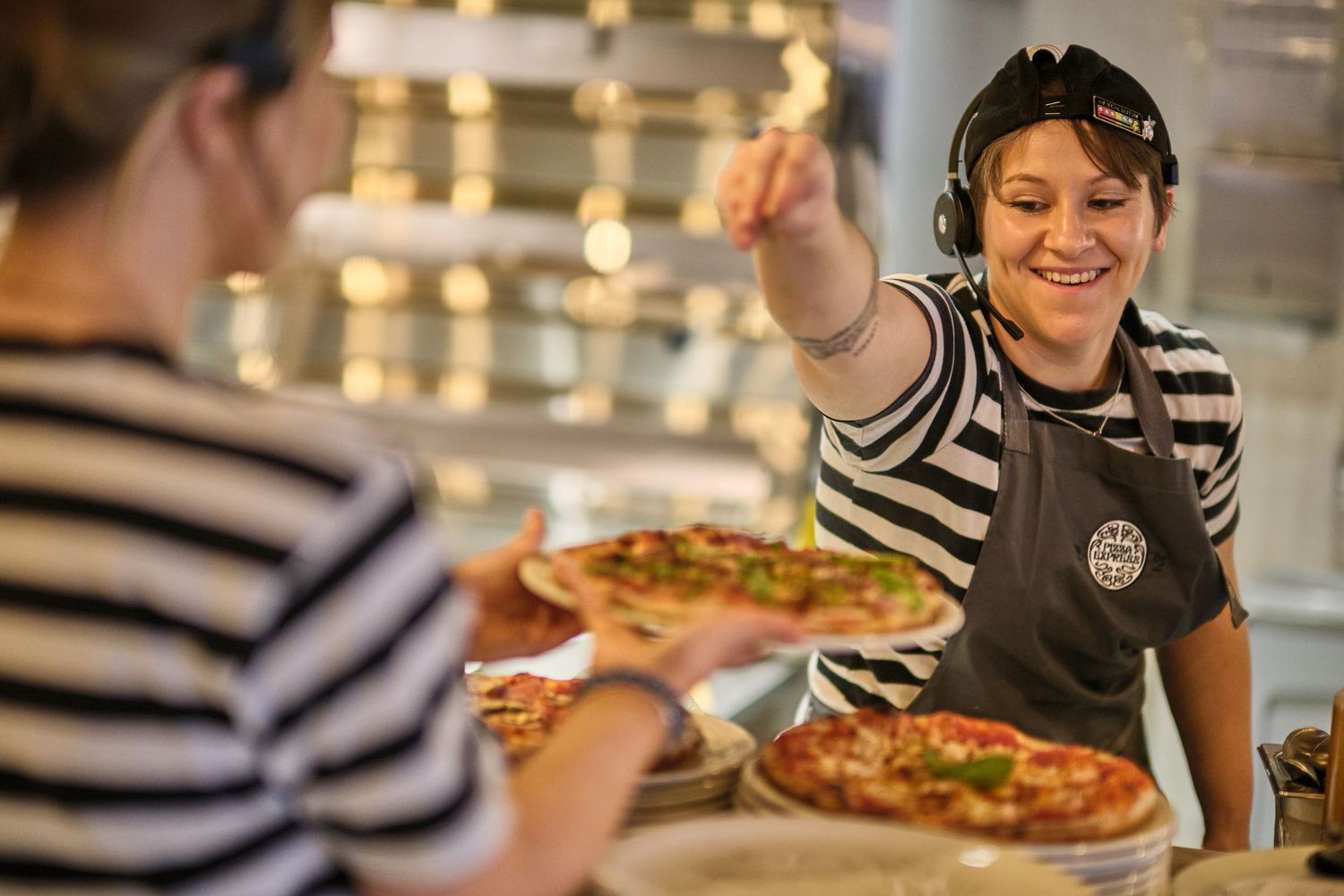 Restaurant staff working together to prepare fresh pizzas in an open kitchen.