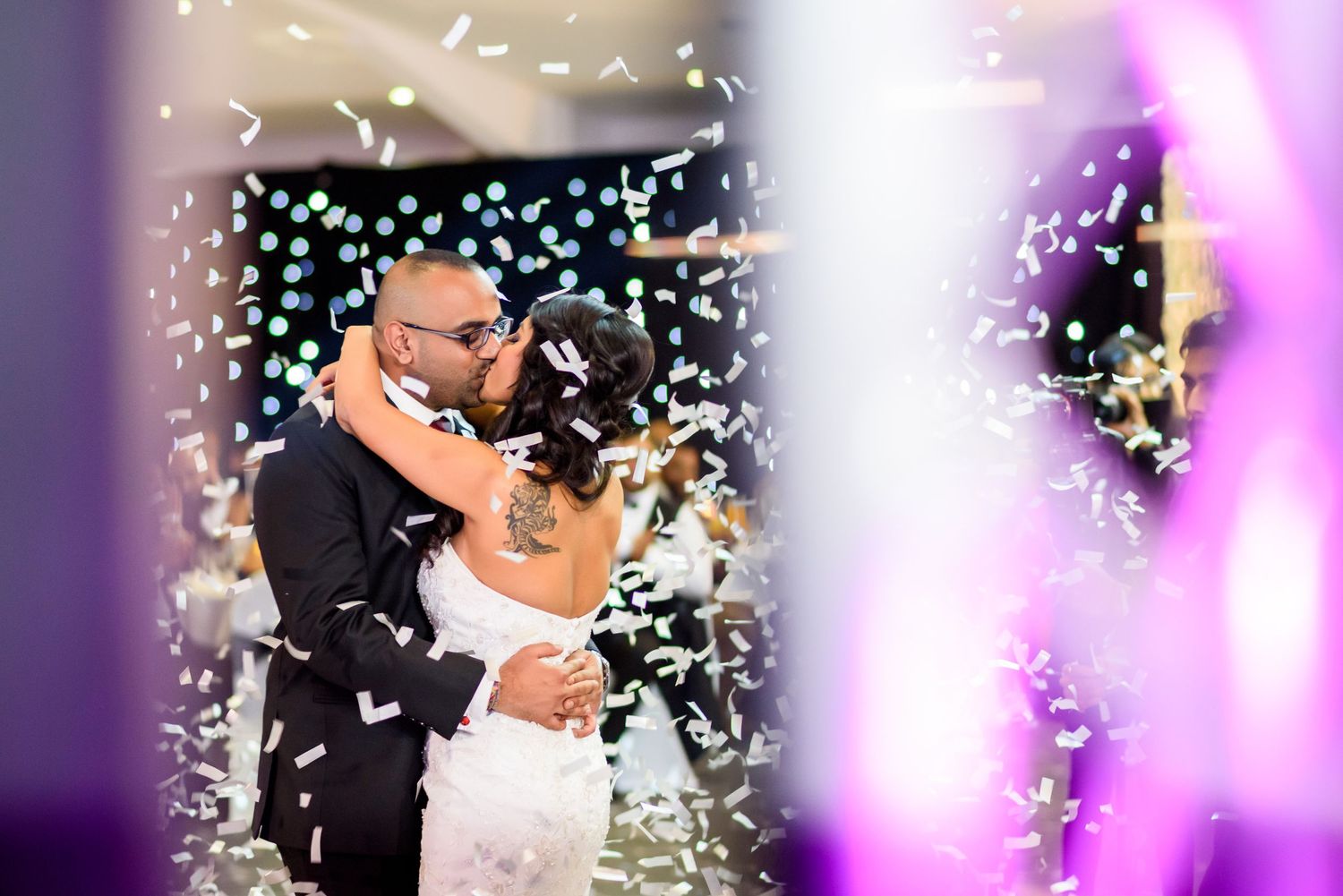 Wedding celebration with confetti falling and purple lighting creating a magical atmosphere.