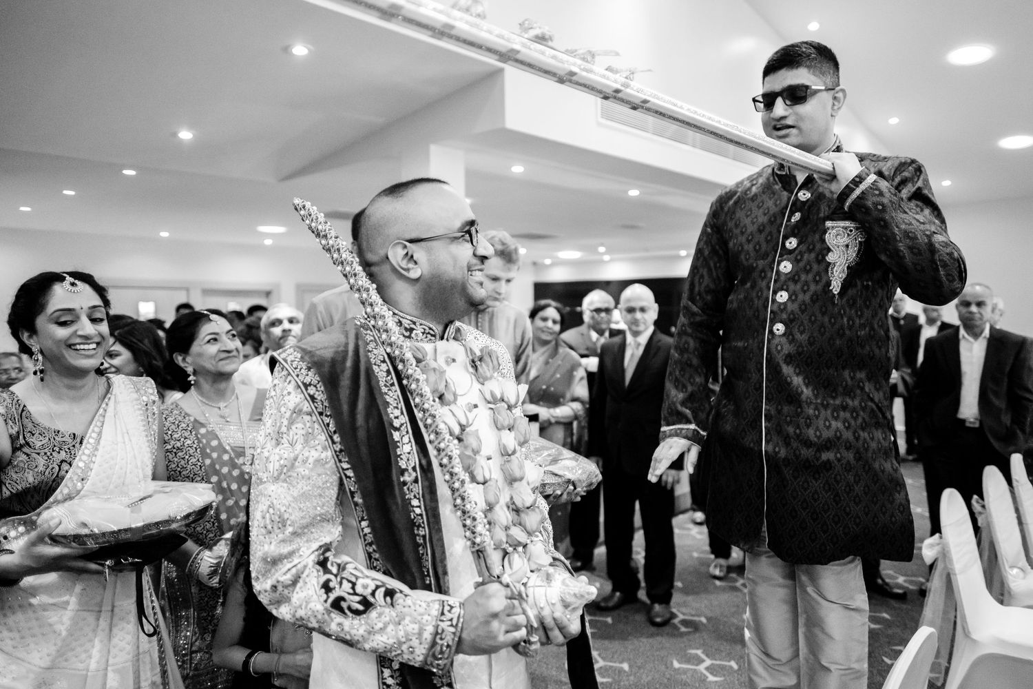 Wedding guests celebrate during a traditional Indian ceremony in a banquet hall.