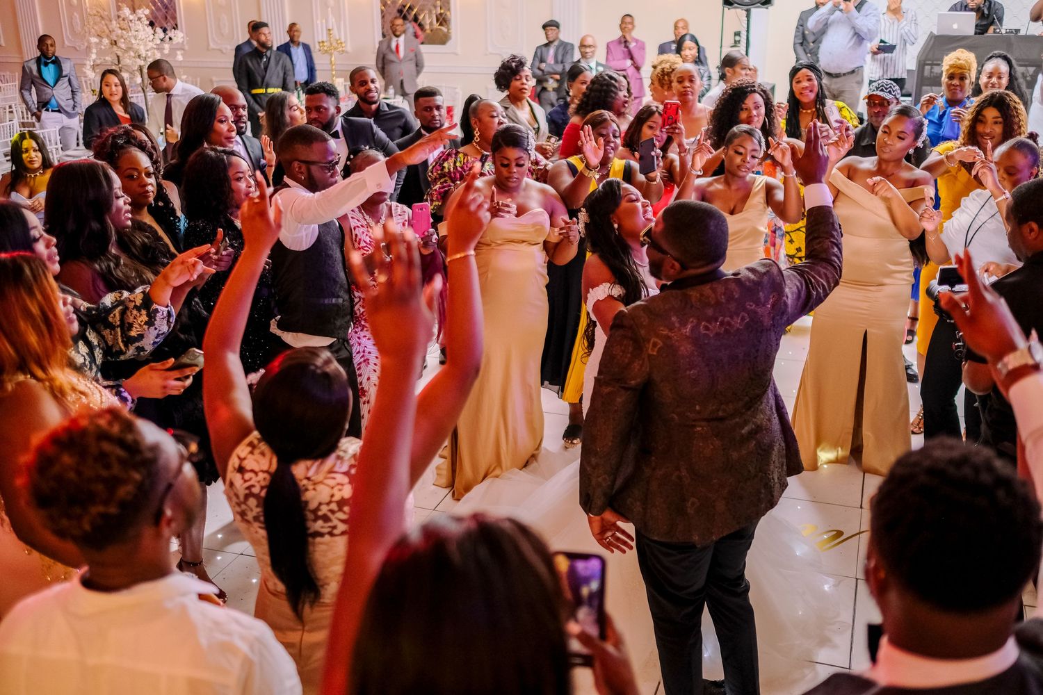Large group of wedding guests dancing and celebrating on a crowded reception dance floor.