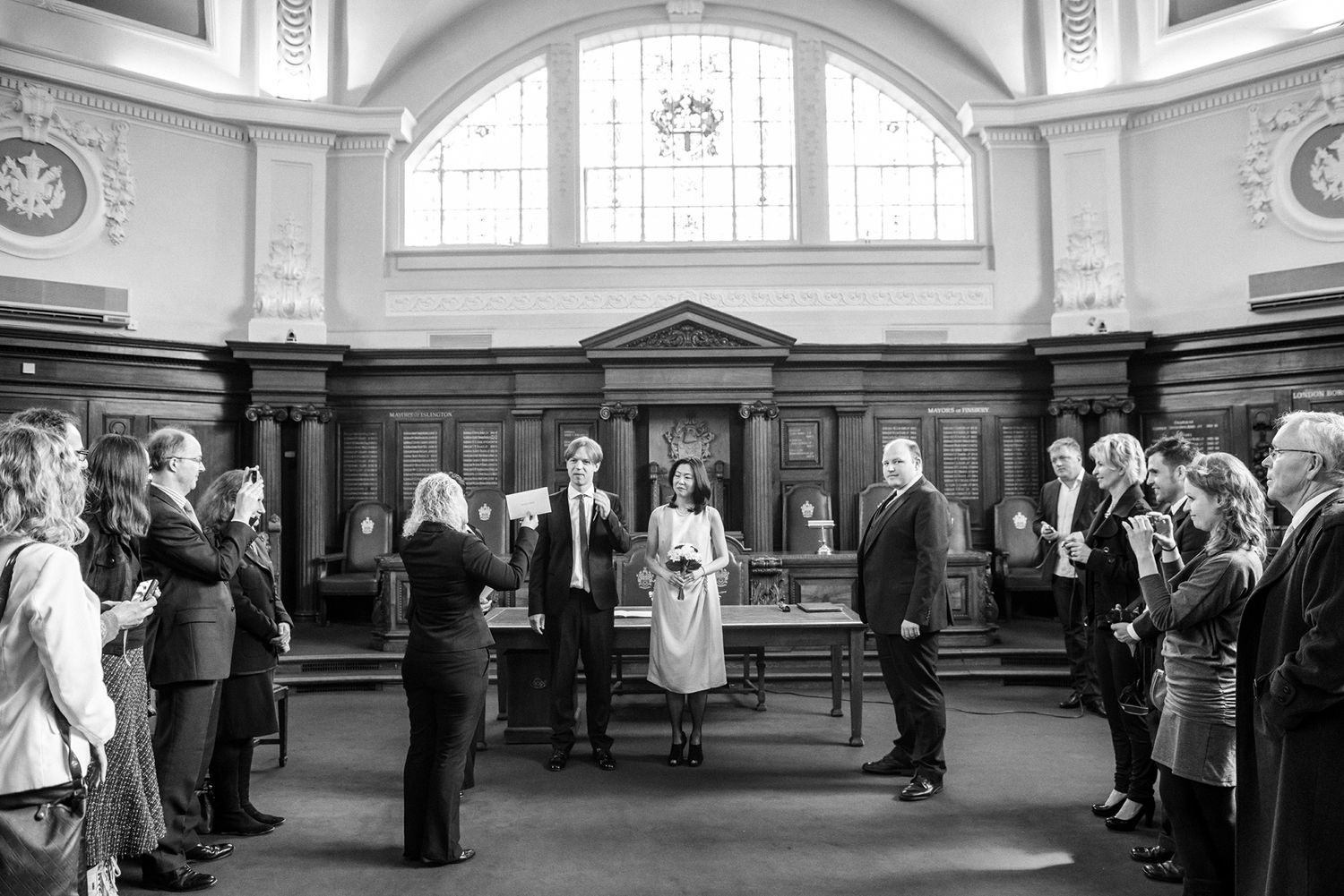 Panoramic view of a grand ceremony hall with arched windows and wooden benches.