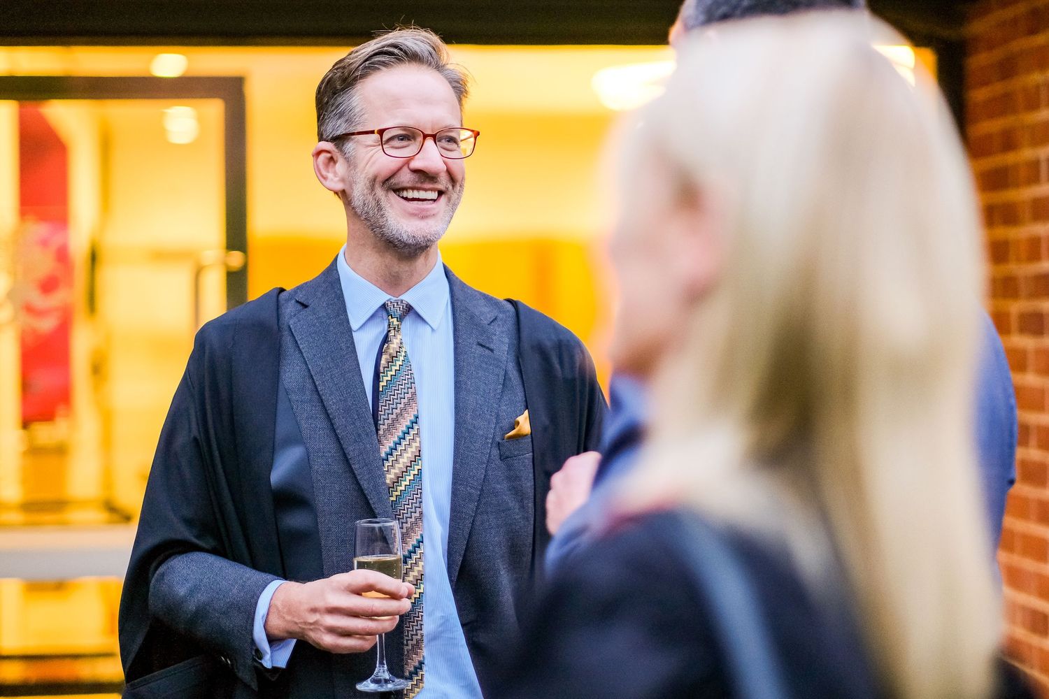 Business professionals gathered in an indoor venue with warm lighting and brick walls.