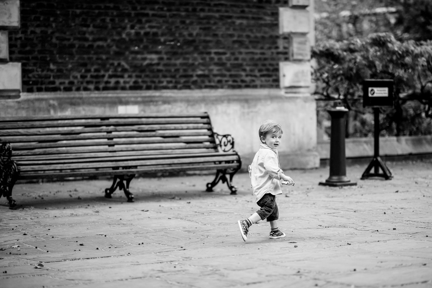 Young person runs in front of brick wall in stylish vintage-inspired black and white photography sequence.