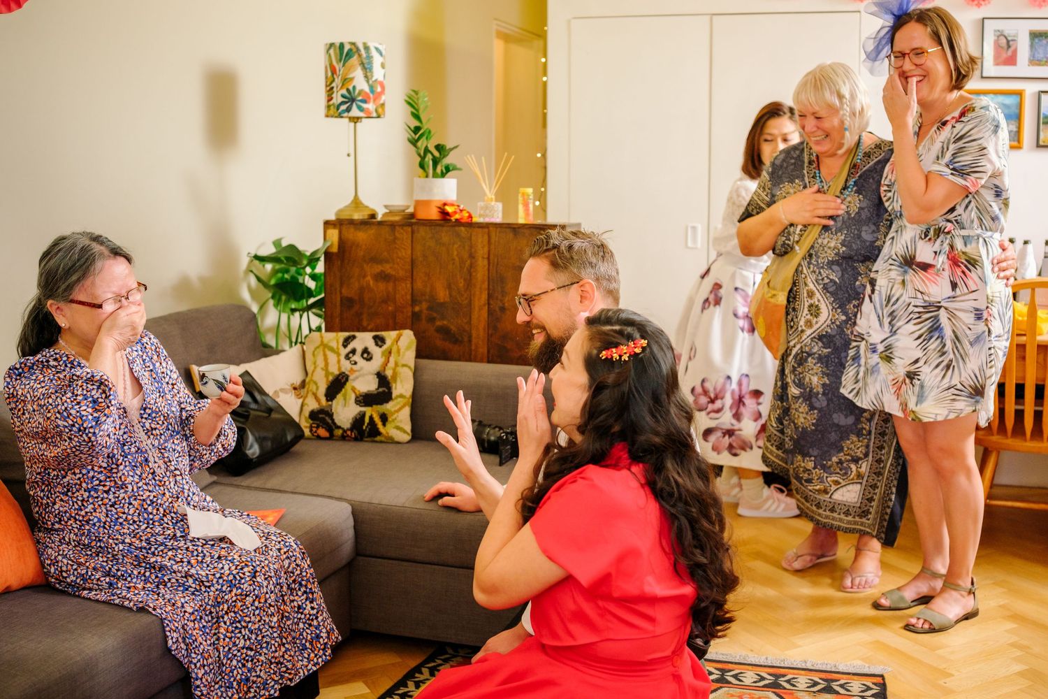 A sequence of photos showing people playing with a dog on a couch in a living room setting.