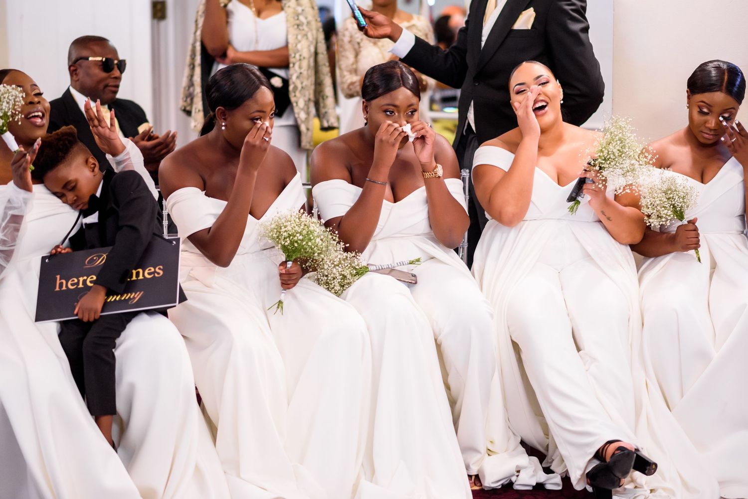 Wedding party members in coordinated white attire pose together during celebration.