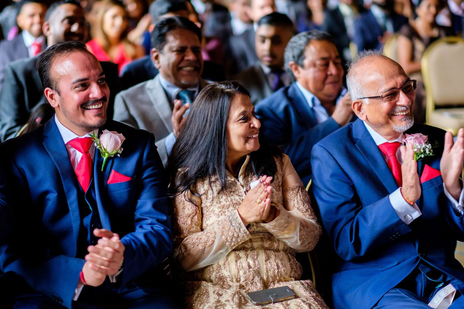 Wedding guests smile and celebrate during an indoor reception.