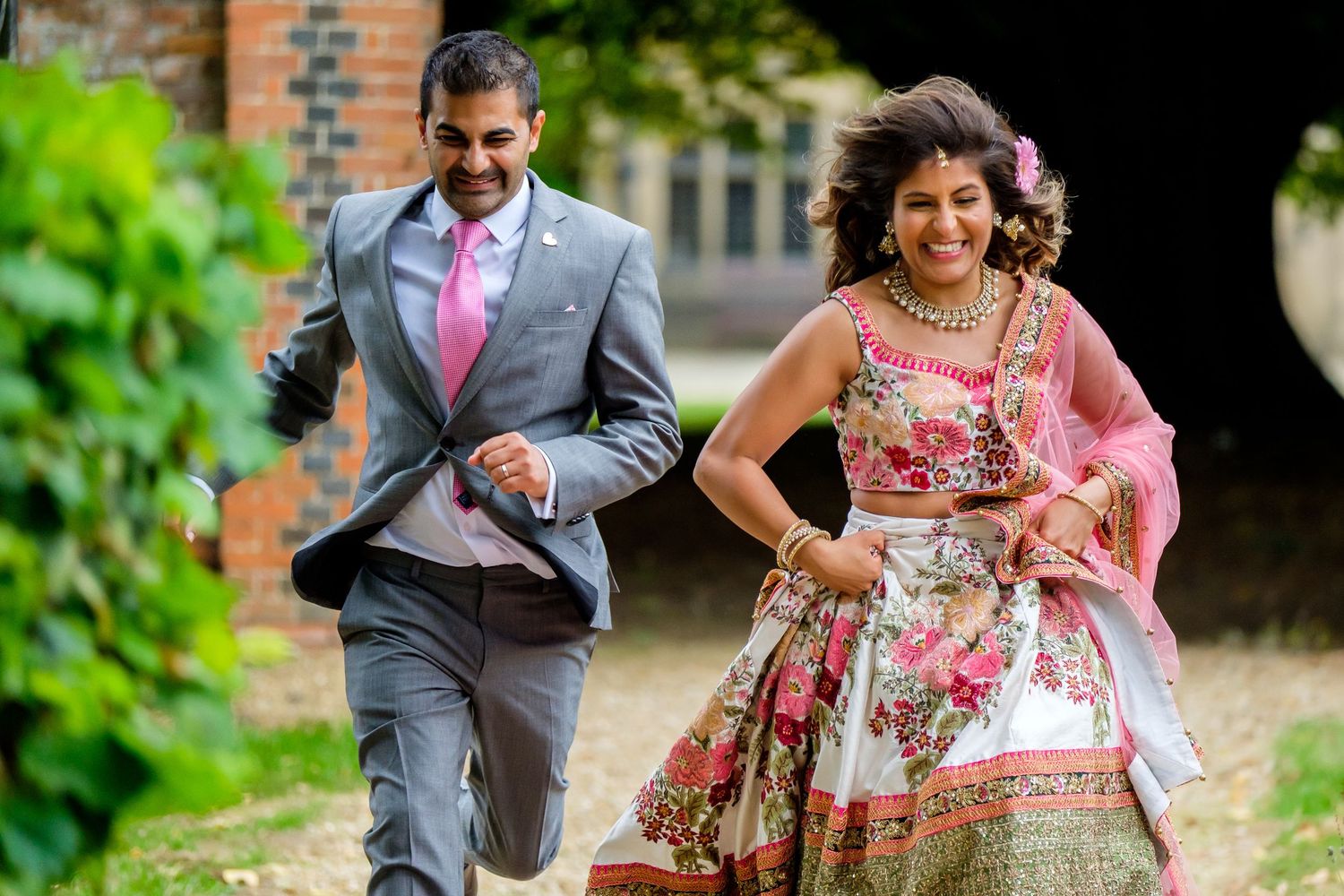Couple in traditional Indian fusion attire posing in outdoor garden setting.