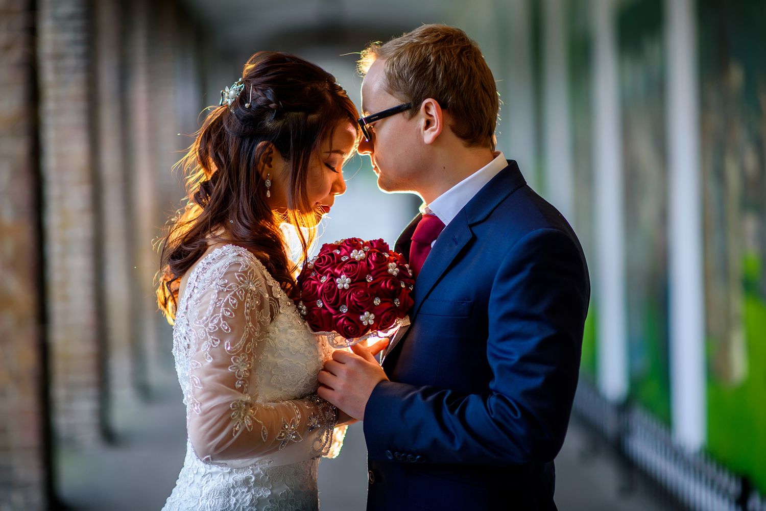 A romantic moment captured between newlyweds in a covered brick walkway.
