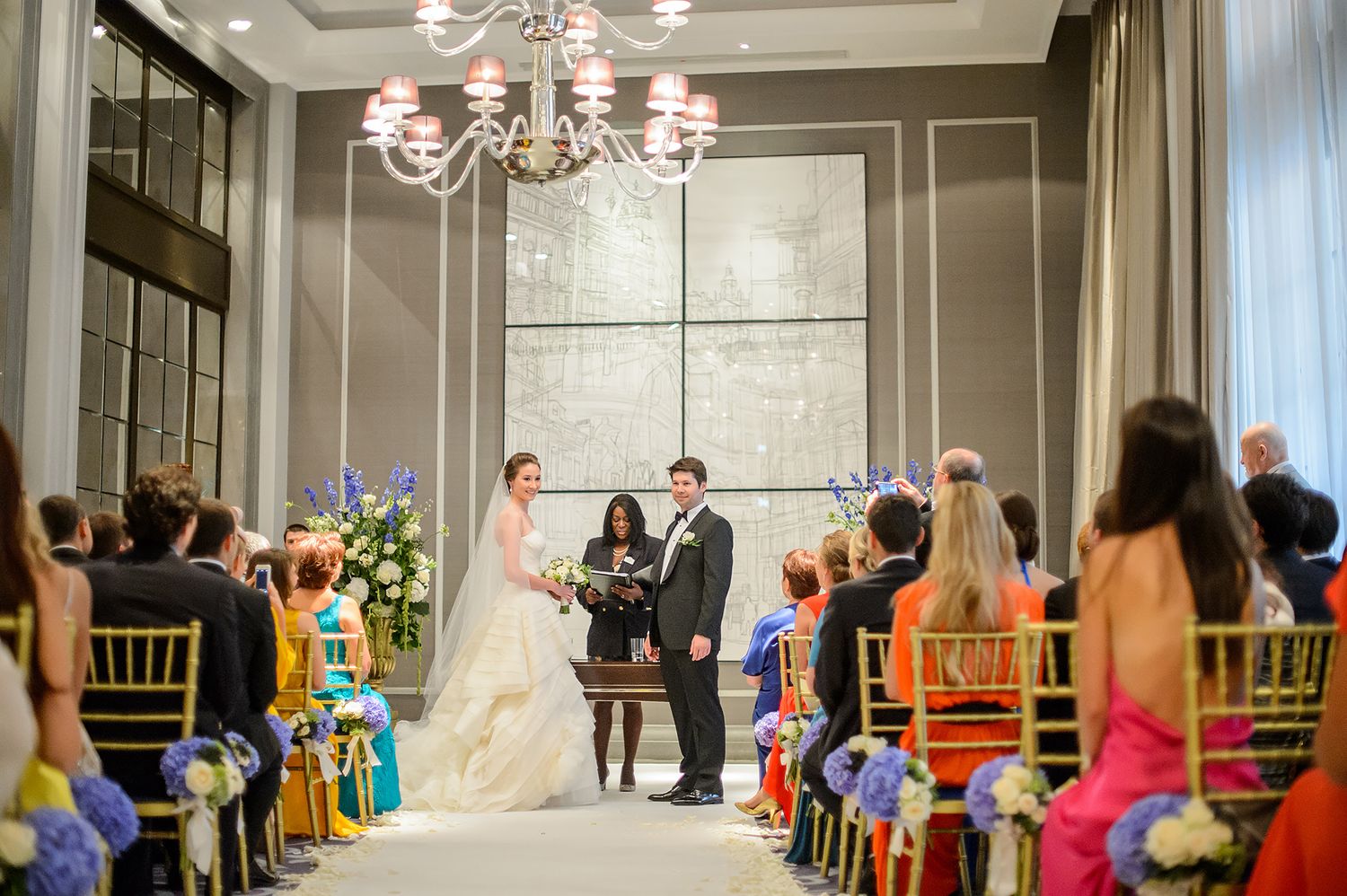 Indoor wedding ceremony setup with elegant chandelier and floral arrangements.