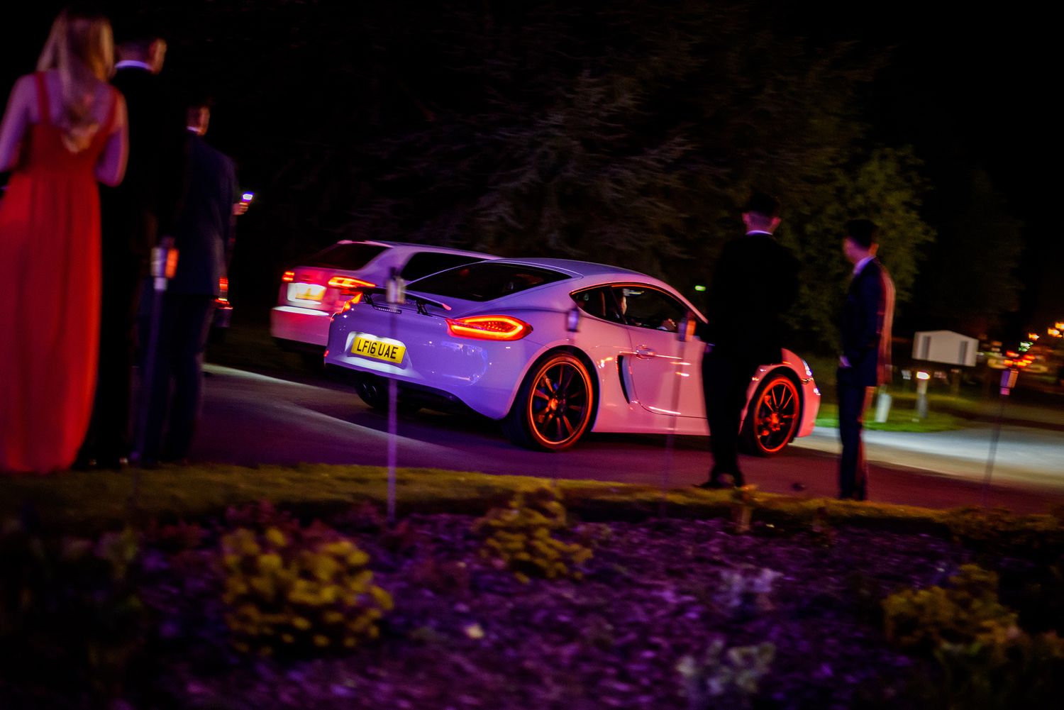 Nighttime exterior shot of cars with colorful lighting effects.