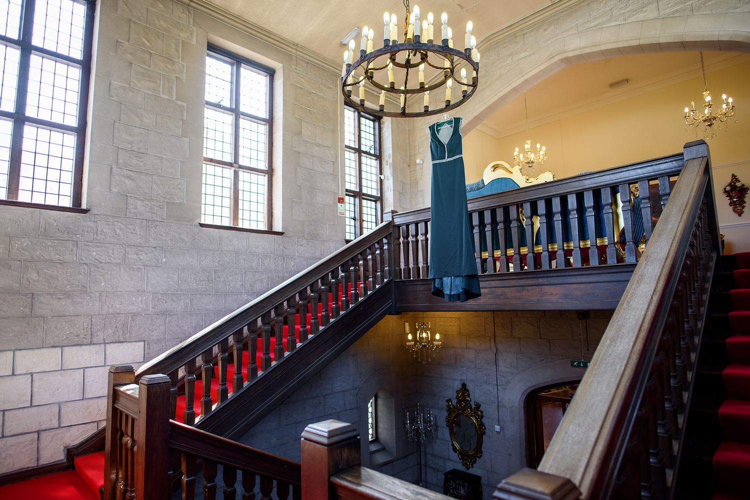 Grand staircase with ornate chandelier and blue railings in historic building interior.