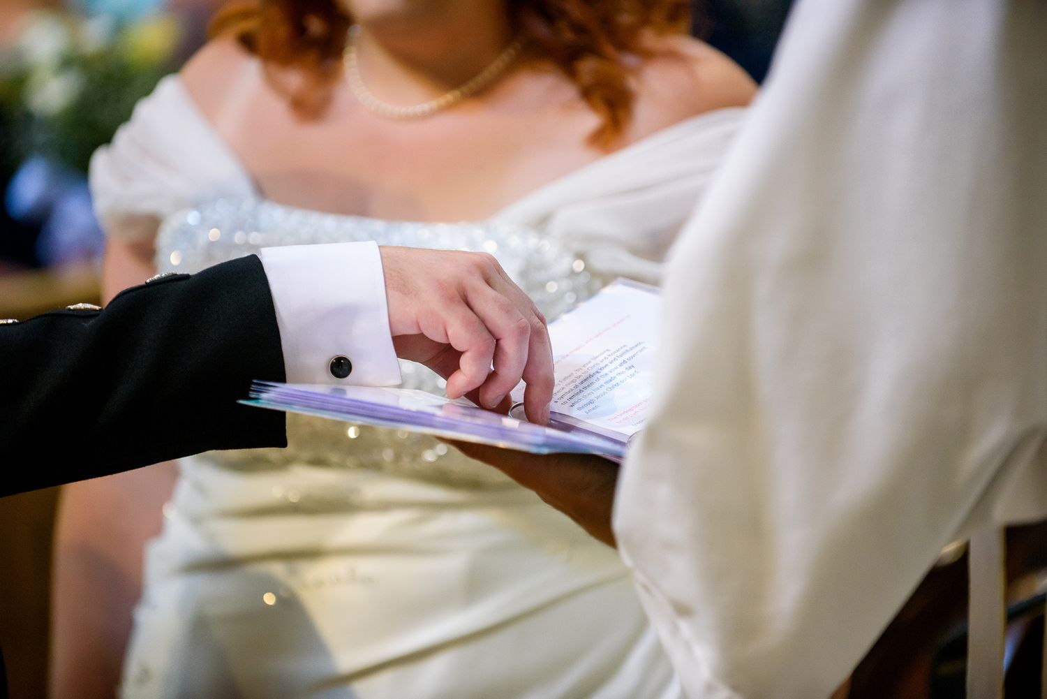 Close-up of hands signing official wedding documents in a ceremony.